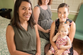 Women and a child sit together in a room. 